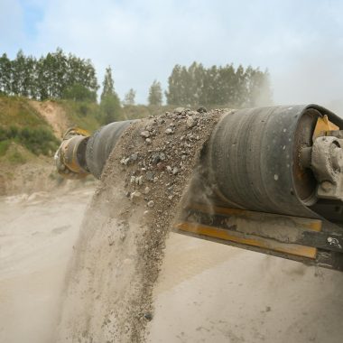 A close-up of an industrial conveyor belt moving gravel at a construction site